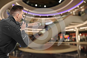 Male security guard using portable radio transmitter in shopping mall