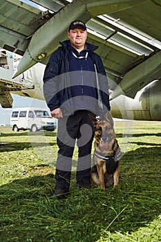 Male security worker with dog standing outdoors at airfield