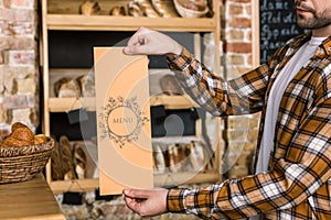 male seller holding paper menu in hands