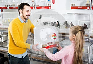 Male seller offering cage with canary bird