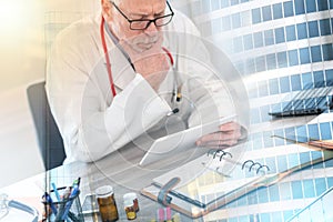 Male senior doctor using digital tablet; multiple exposure