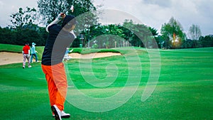 Male senior golfer swinging golf ball in a nature green grass fairway. Professional golf player drive the ball to the hole.