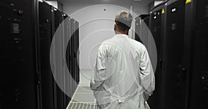 Male Server Engineer Walks Through Working Data Center Full of Rack Servers