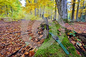 Male set - knives and watches. Black knife and smart watch in autumn forrest