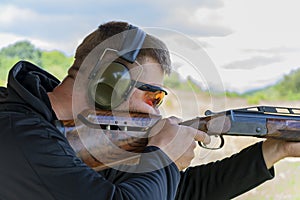 A male shooter aims a sporting double-barreled hunting rifle, target shooting, bench shooting.