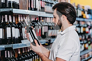 male shop assistant arranging alcohol photo