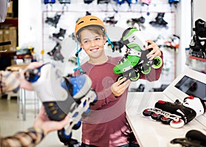 Male shop assistant helping boy to choose roller-skates in sports store