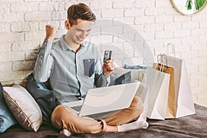 Male shopper celebrating sucessful shopping at online retail store photo