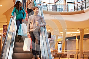 Male Shopper On Escalator In Shopping Mall