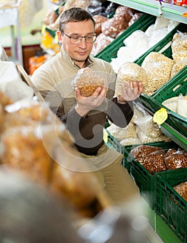 Male shopper selects various nuts in the produce section of supermarket photo
