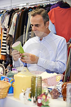 Male Shopper In Thrift Store Looking At Ornaments photo