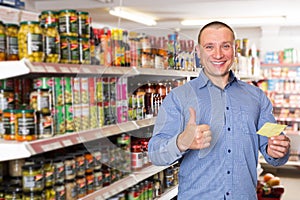 Male with shopping list holding thumb up in supermarket