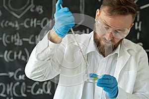 Male sientist dropping pipette a sample into a Petri dish with green plant in laboratory, Biotechnology