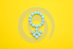 Male sign made of blue pills on yellow background  flat lay. Potency problems