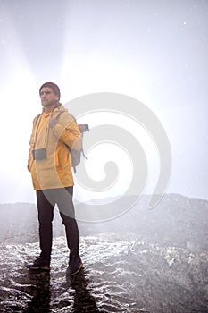 Male silhouette with camera walking down the mountain, at foggy weather, alone