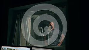 Male singer in headphones singing song into the microphone at sound studio. Show business concept. Adult man recording a