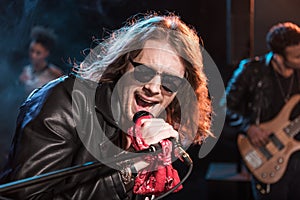 Male singer with microphone and rock and roll band performing hard rock music