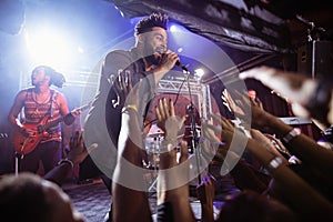 Male singer performing on stage by crowd at nightclub