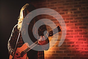 Male singer practicing with guitar in nightclub