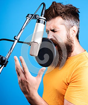 Male singer singing in condenser microphone. Professional vocalist in studio. Music, leisure concept.