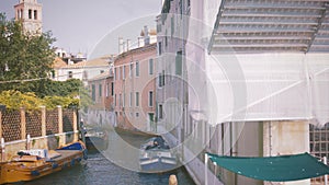 Male sits in a moored boat on a canal in Venice in the evening