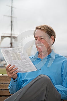 Male sitting on a bench with court papers in his hadn