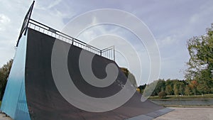 Male skater with a naked torso make turns in ramp, wide angle view in slowmo