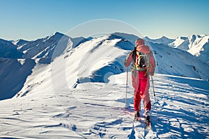 Male ski tourer enjoying the view on a summit in the alps