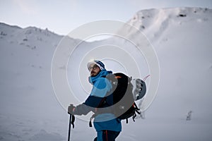 Male skier in bright jacket is climbing the hill using skitour equipment. photo