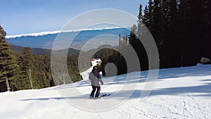 Male skier dressed in black, man skiing down a tree lined snowy mountain piste or slope on fresh snow