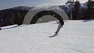 Male skier dressed in black, man skiing down a tree lined snowy mountain piste or slope on fresh snow