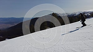 Male skier dressed in black, man skiing down a tree lined snowy mountain piste or slope on fresh snow