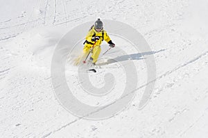 A male skier freerider with a beard descends the backcountry at high speed from the slope