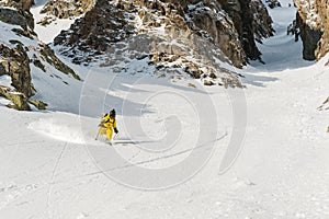 A male skier freerider with a beard descends the backcountry at high speed from the slope