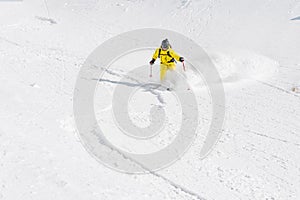 A male skier freerider with a beard descends the backcountry at high speed from the slope