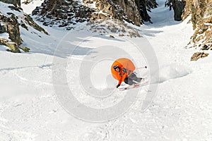 A male skier freerider with a beard descends the backcountry at high speed from the slope