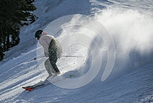 Male skier going downhill on a high speed leaving fresh powder snow behind. Active lifestyle and sport concept.