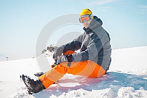 Male skier sitting on snow relaxing