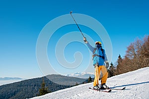 Male skier using selfie stick taking photos while skiing