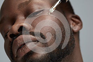 Male Skin Care. Face Beauty Procedure For African Model. Oil Vitamins Treatment For Facial Restore And Renewal. photo