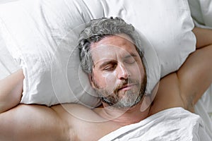 Male sleeps on pillow. Gray hair man sleep in white bed. Senior man sleep in bed at bedroom. Mature man morning sleeps