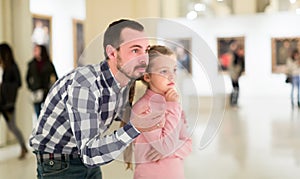 Male and small daughter looking pictorial art in halls