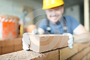 Male smiling builder puts make brickwork