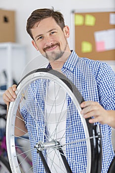 male smiling master holding bike wheel photo