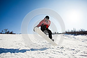 Male snowboarder in action jumping over hill