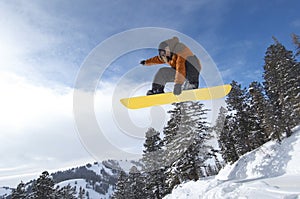 Male Snowboarder Jumping Over Snow Covered Hill