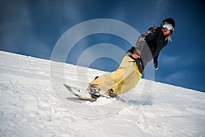 Male snowboarder riding down the mountain slope