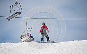 Male snowboarder riding down from the mountain in winter day