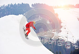 Male snowboarder riding from the top of the snowy slope with snowboard at winter ski resort