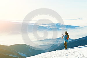 Male snowboarder taking photo of the beautiful landscape with sun-set